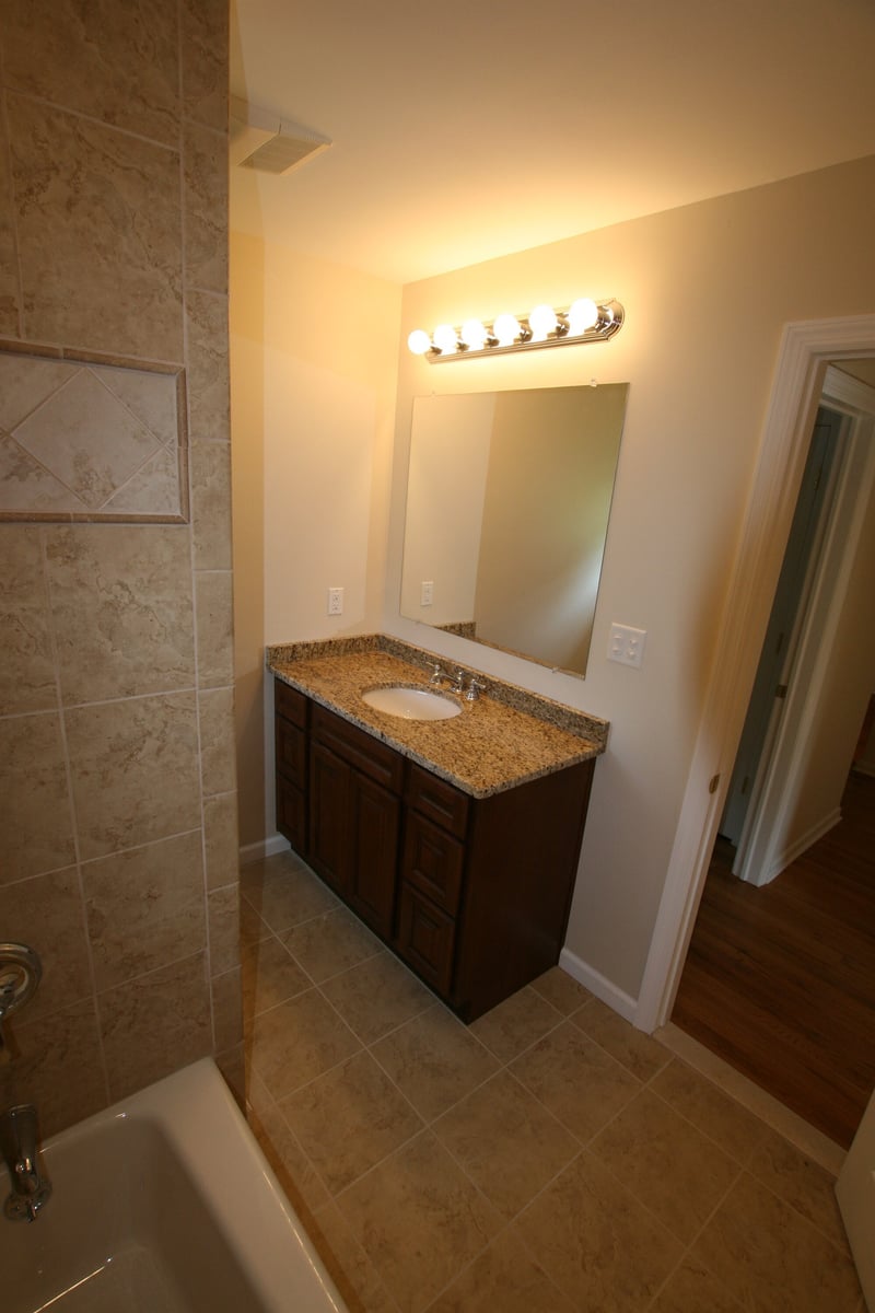 bathroom vanity with framed mirror and tiled tub surround custom home project by houghton contracting in ewing new jersey