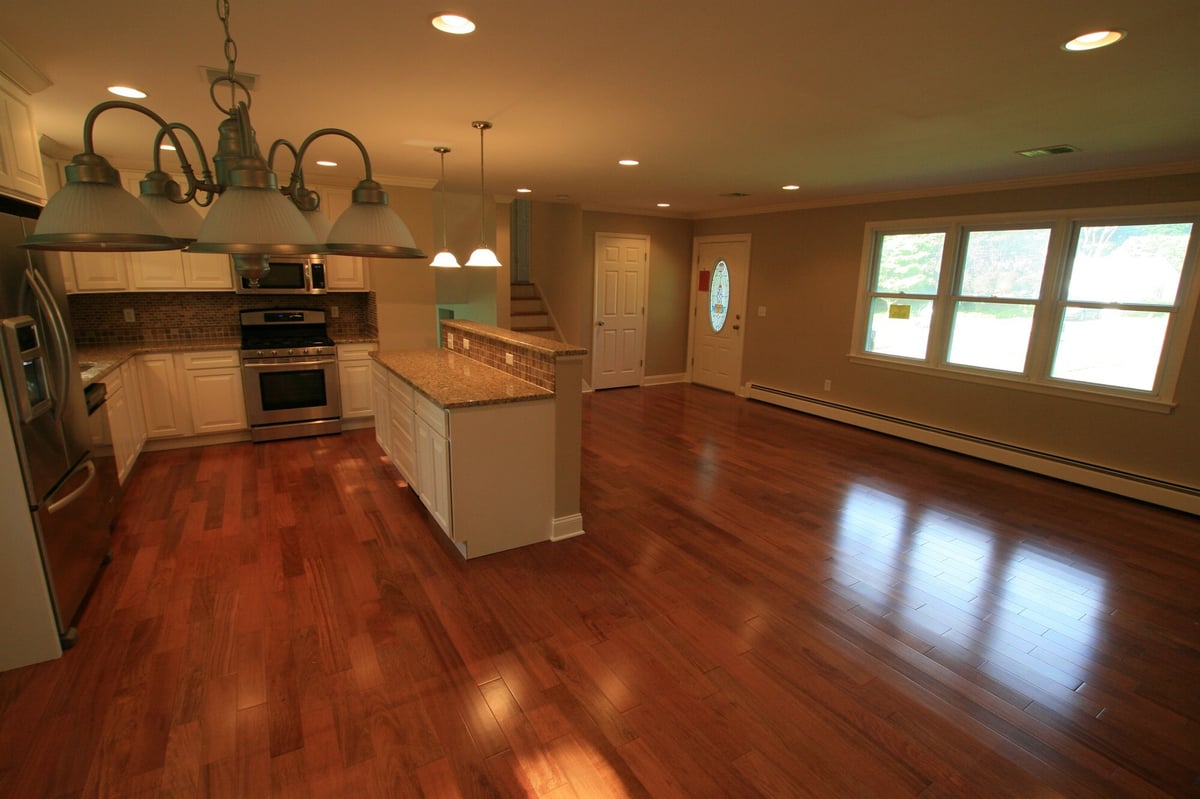 great room and kitchen with gooseneck island chandelier and triple window houghton contracting custom home project in ewing new jersey