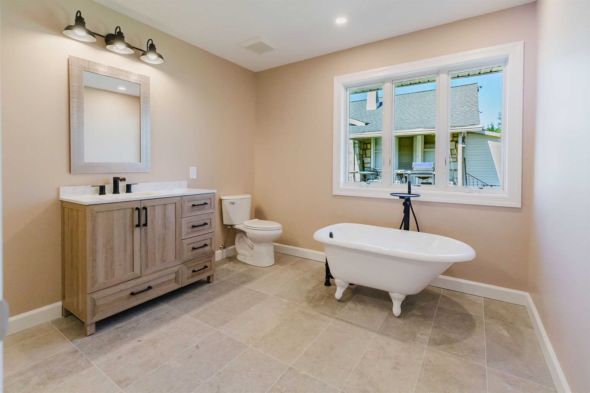 primary bathroom with clawfoot tub wood vanity and farmhouse lighting home addition project by houghton contracting in lawrenceville new jersey-optimized